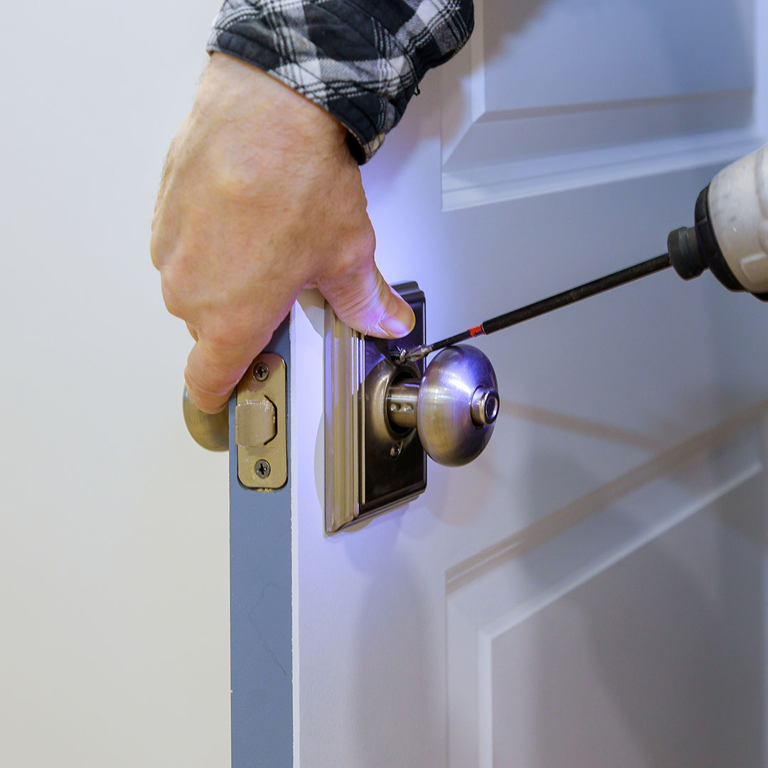 master-with-screwdriver-installs-access-room-door-new-lock-house